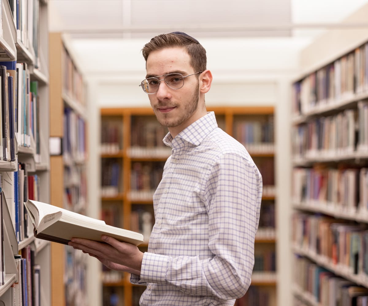 student holding book in library