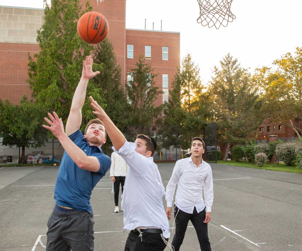 Students playing basketball on an outdoor court on campus