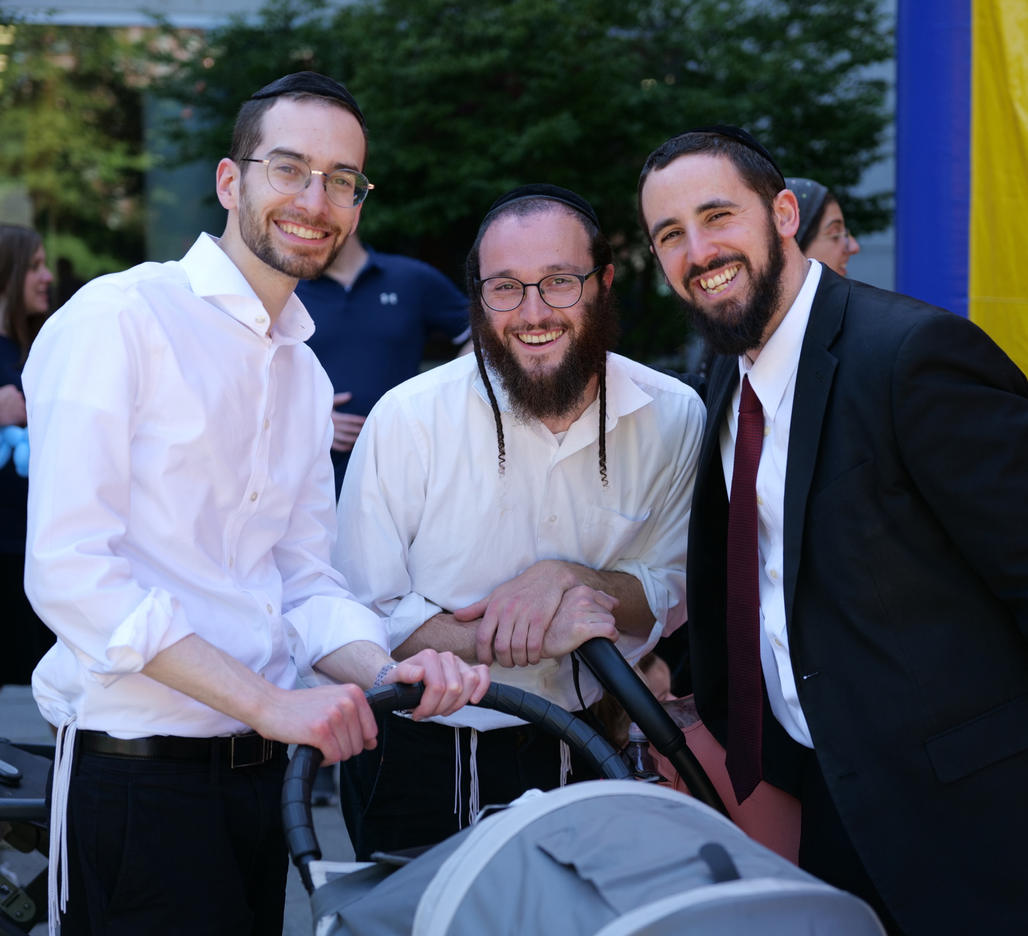 Three alums smiling together with child's stroller in front of them